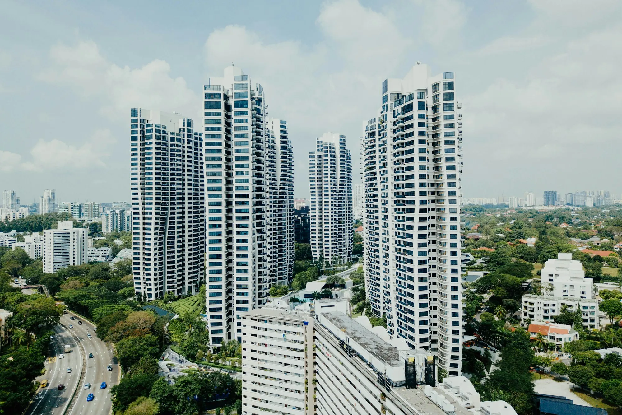 Slender residential towers rising above a green waterfront downtown