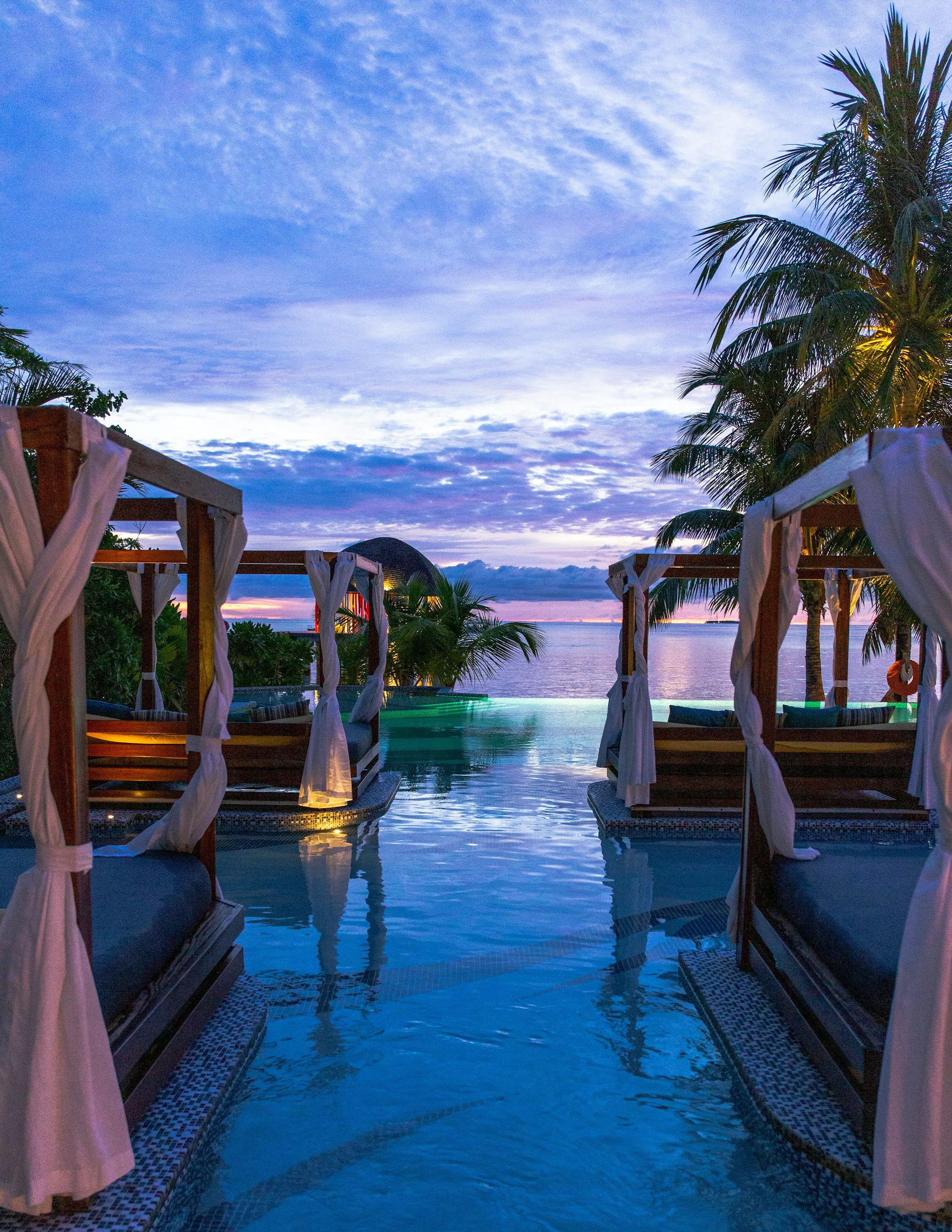 A palm-lined pool terrace lit at dusk on the Gulf Coast