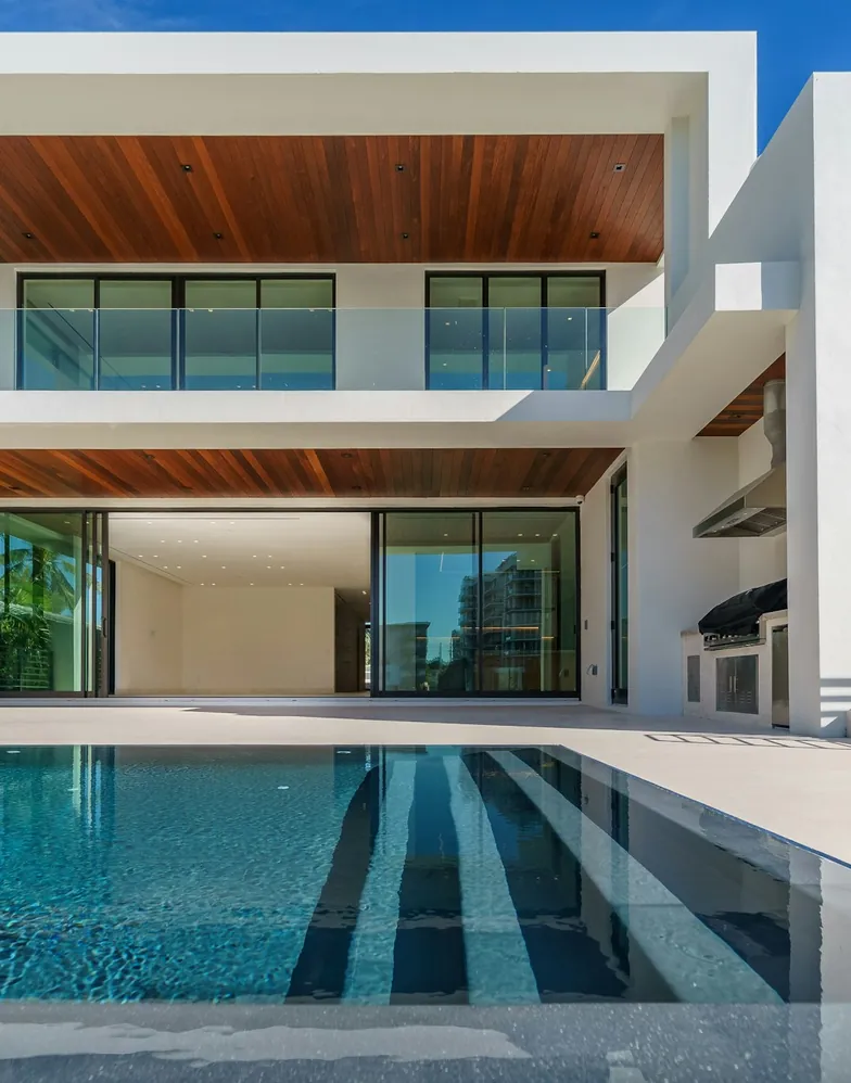 A white contemporary Florida villa with a lap pool at dusk