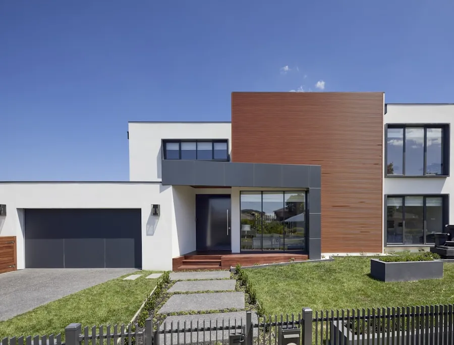 A contemporary house with a stone facade and lawn
