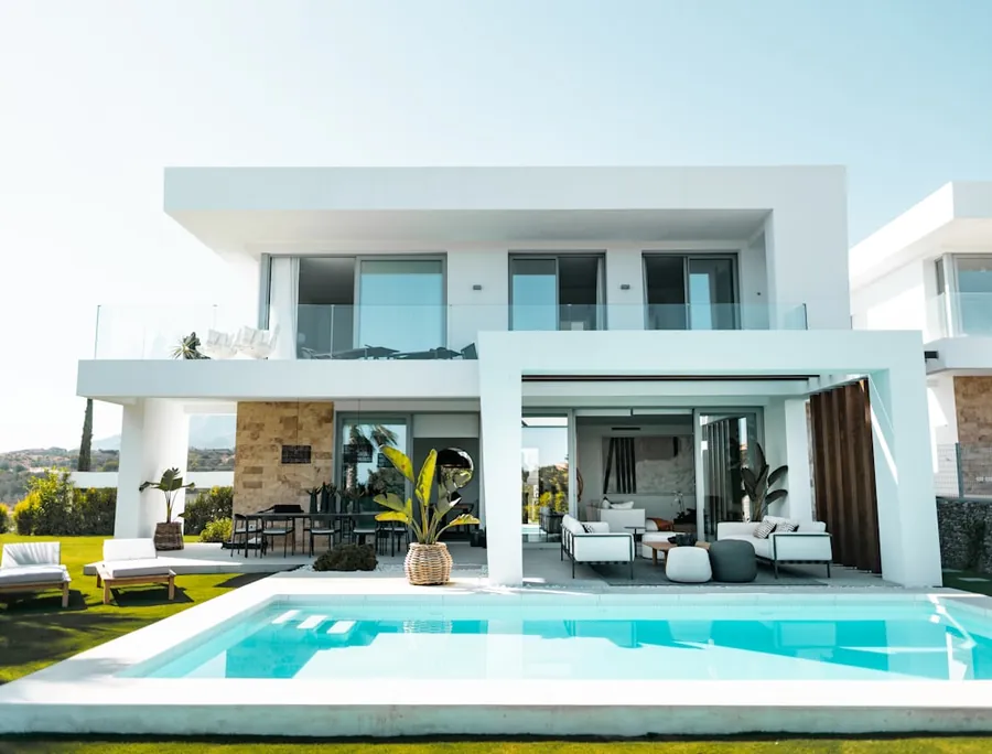 A white waterfront home with an infinity pool at golden hour